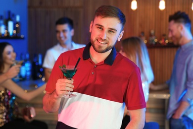 Young man with glass of martini cocktail at party