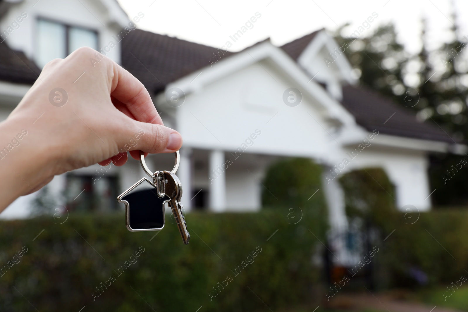 Photo of Woman holding house keys outdoors, closeup with space for text. Real estate agent