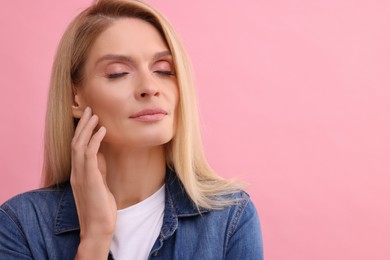 Portrait of beautiful middle aged woman with blonde hair on pink background. Space for text