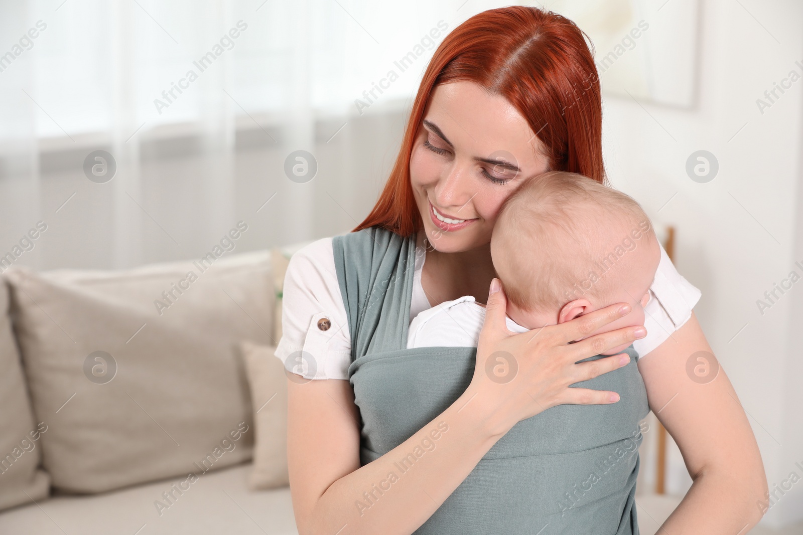 Photo of Mother holding her child in sling (baby carrier) at home