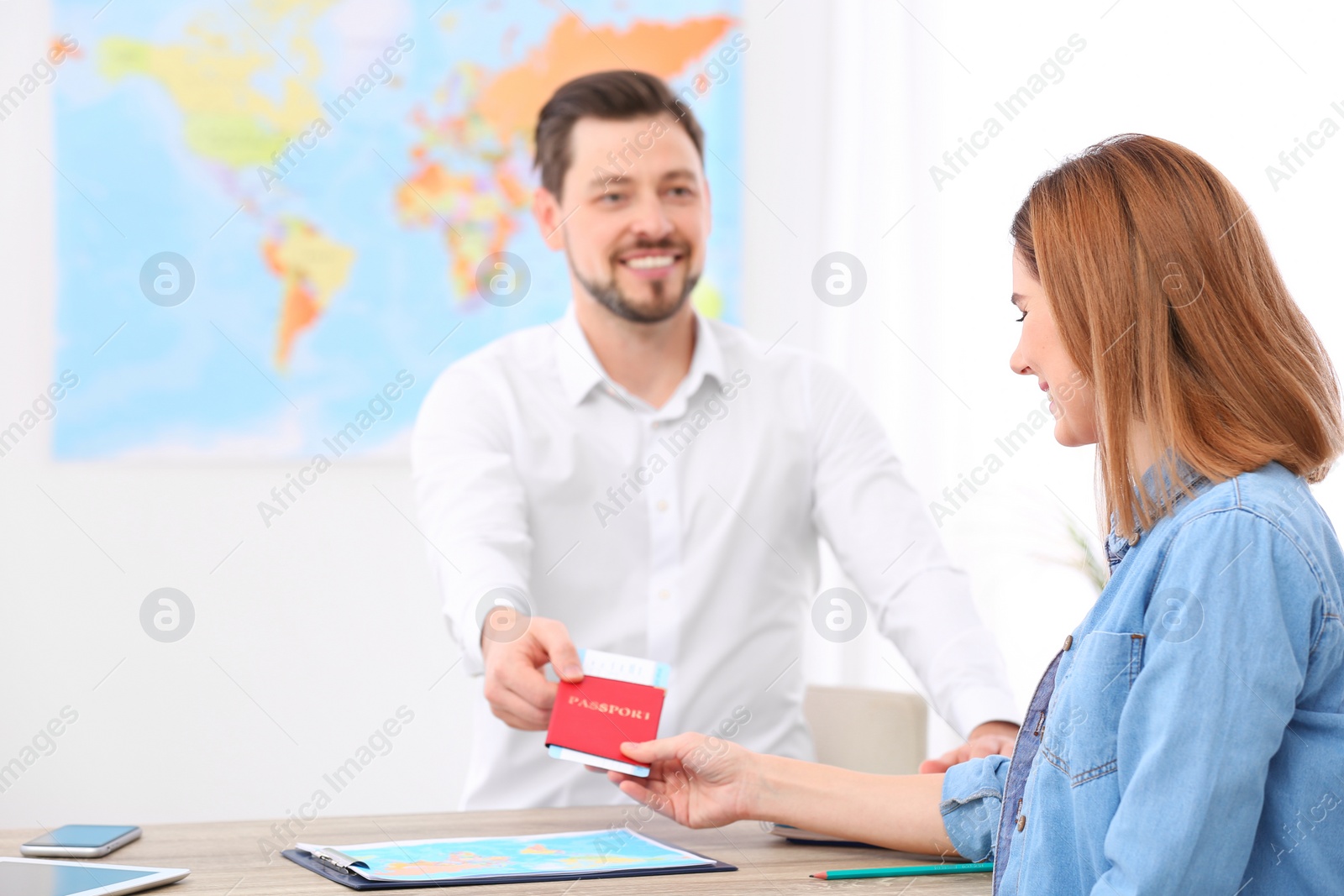 Photo of Male manager giving passport with ticket to client in travel agency