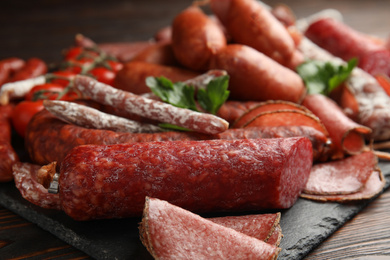 Different tasty sausages on wooden table, closeup