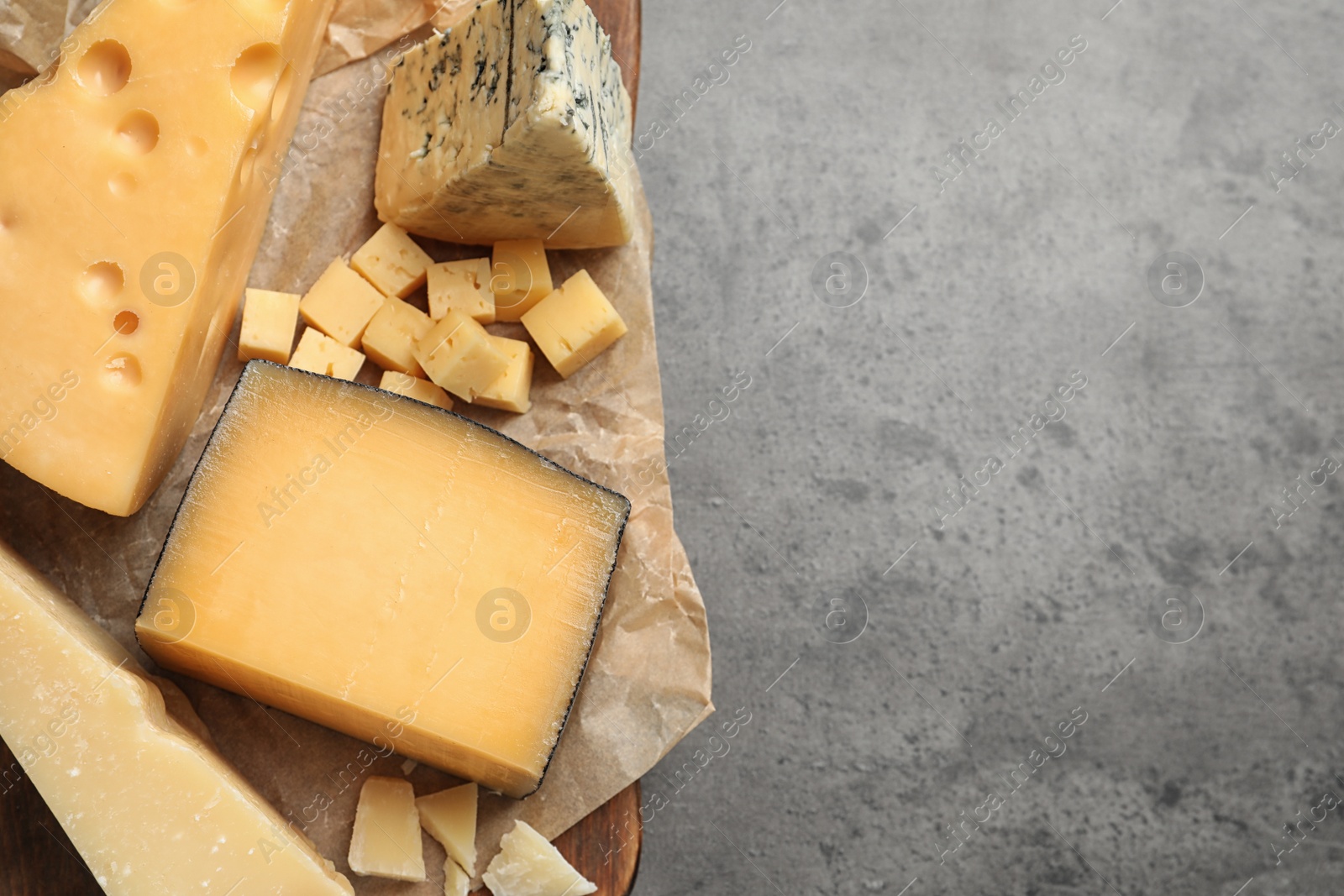 Photo of Different types of delicious cheese on grey table, top view. Space for text
