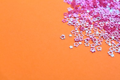 Shiny bright star shaped glitter on pale coral background. Space for text