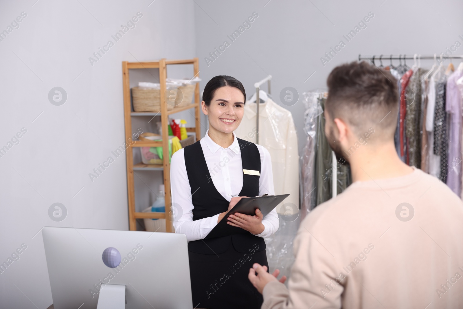 Photo of Dry-cleaning service. Happy woman working with client indoors