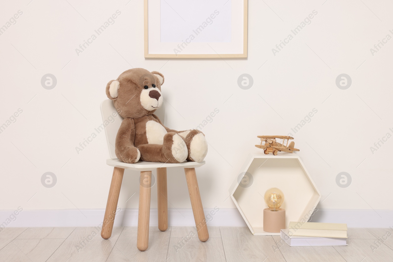 Photo of Beautiful children's room with light wall, furniture and toys. Interior design