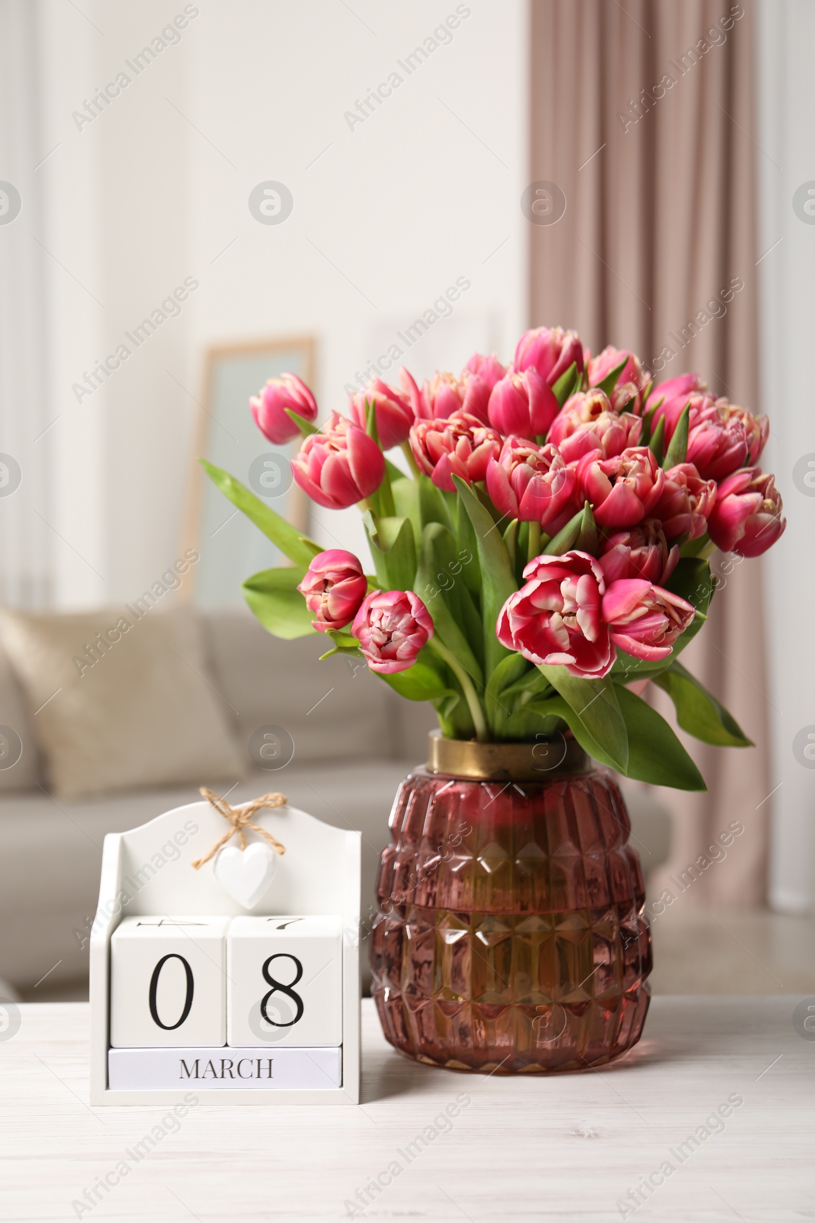 Photo of International Women's day - 8th of March. Block calendar and bouquet of beautiful tulips on white wooden table