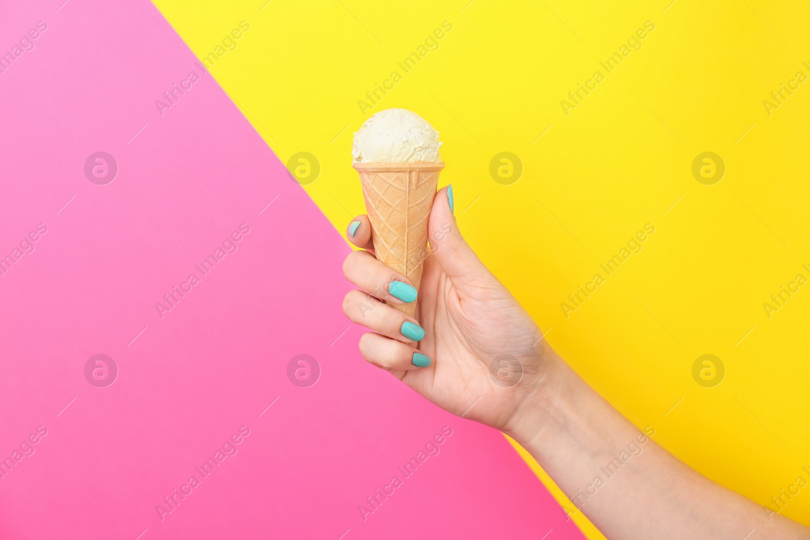 Photo of Woman holding yummy ice cream on color background. Focus on hand