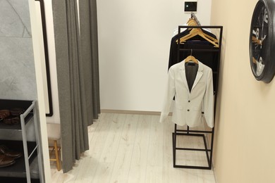 Photo of Dressing room with clothing rack in fashion store. Stylish design