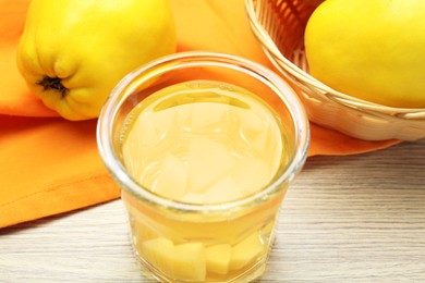 Delicious quince drink in glass and fresh fruits on wooden table, closeup