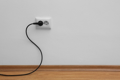 Photo of Power socket and plug on wall indoors, space for text. Electrician's equipment