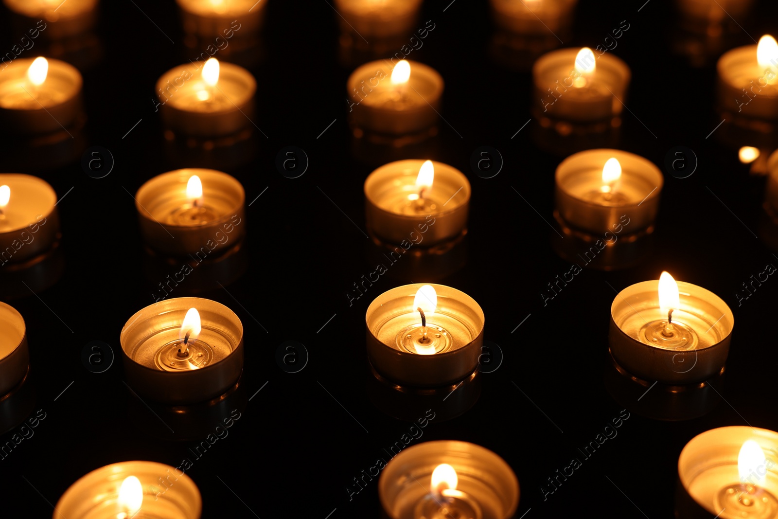 Photo of Burning candles on mirror surface in darkness