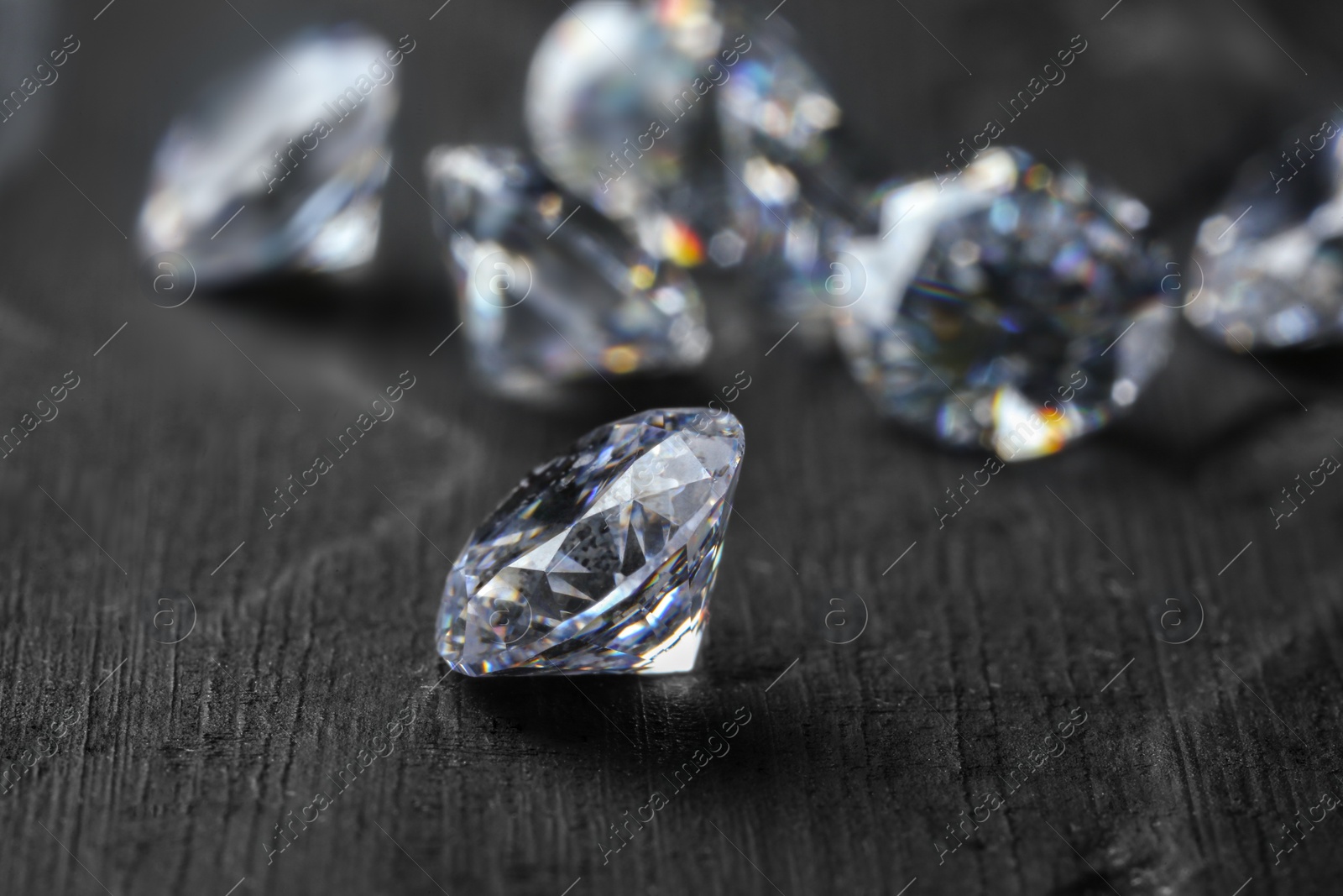 Photo of Beautiful shiny diamonds on dark gray table, closeup