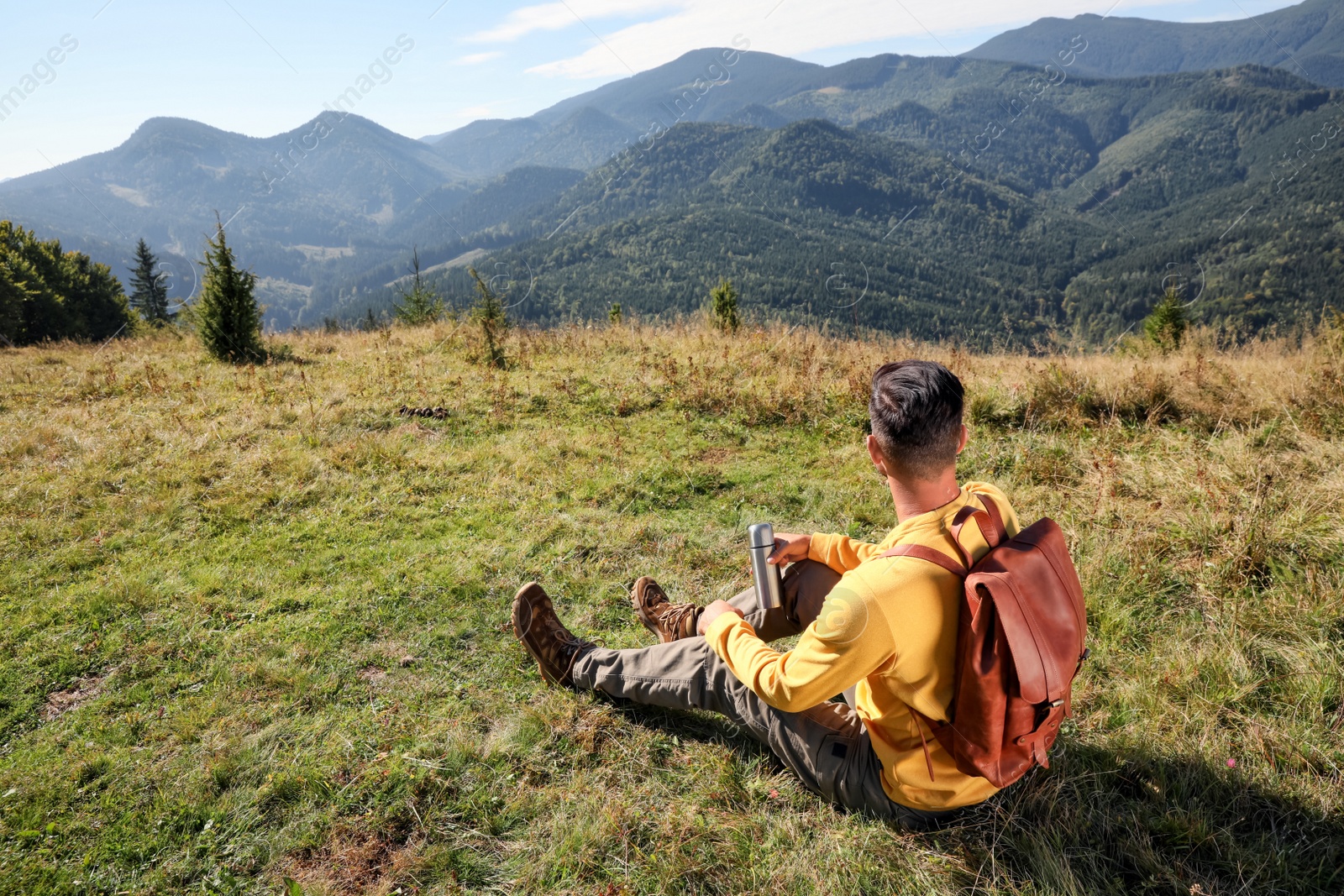 Photo of Tourist with thermos and backpack enjoying beautiful mountain landscape