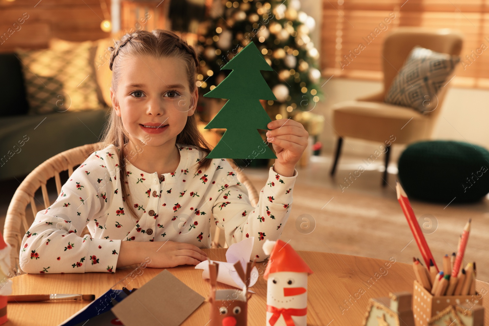 Photo of Cute child holding felt fir tree at home. Making Christmas decor