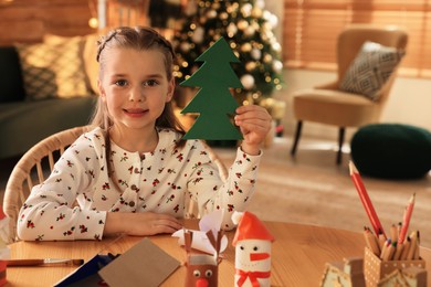 Cute child holding felt fir tree at home. Making Christmas decor