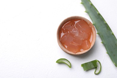 Aloe vera gel and slices of plant on white background, flat lay. Space for text