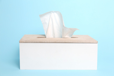 Photo of Holder with paper tissues on light blue background