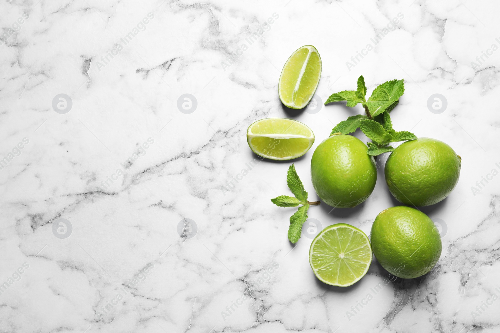 Photo of Fresh ripe limes on marble background, top view