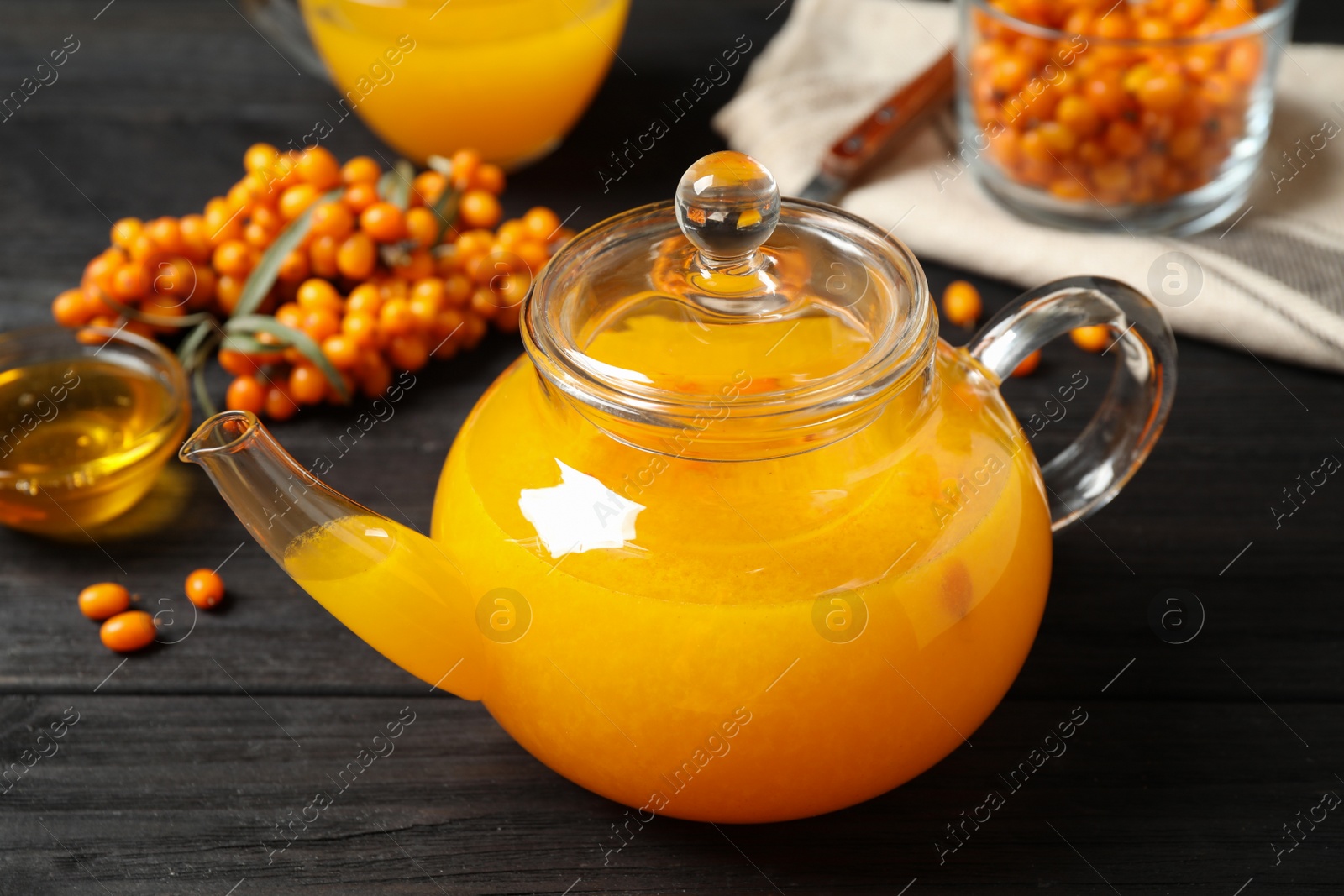 Photo of Delicious sea buckthorn tea and fresh berries on black wooden table