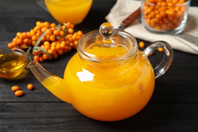 Photo of Delicious sea buckthorn tea and fresh berries on black wooden table