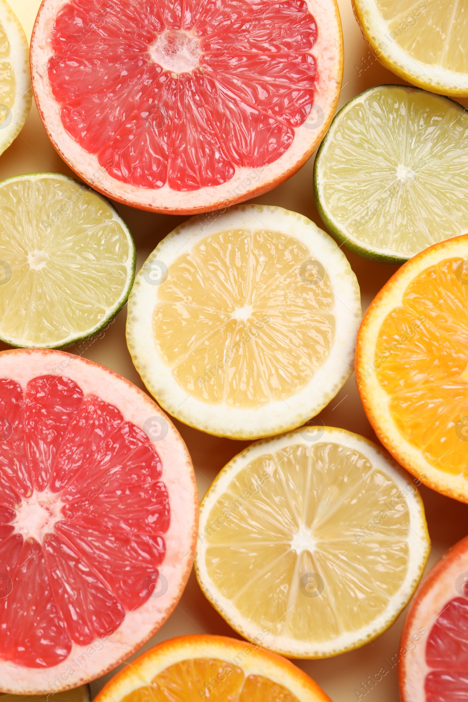 Photo of Different cut citrus fruits on beige table, flat lay