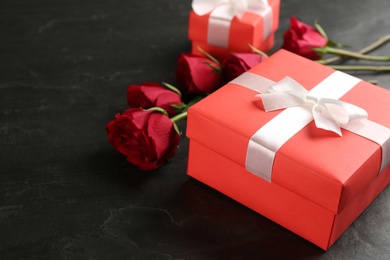 Photo of Beautiful gift box and roses on black table, space for text. Valentine's Day celebration