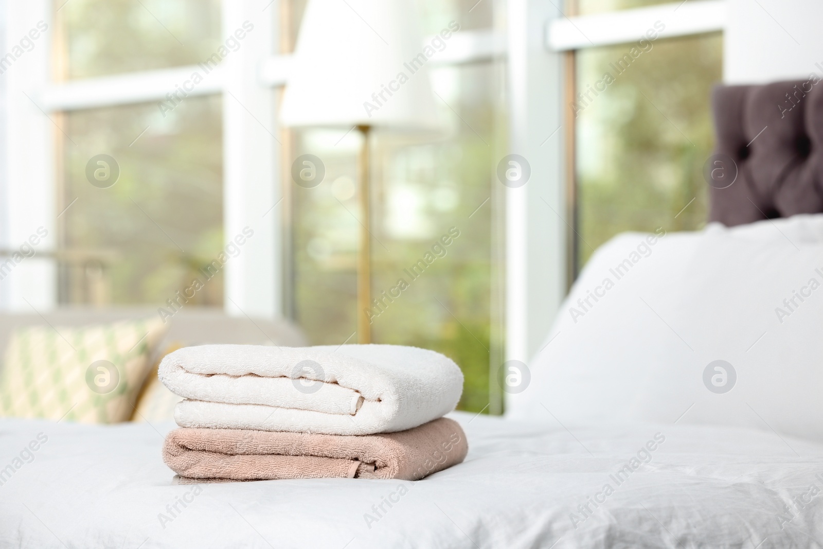 Photo of Stack of clean terry towels on bed. Space for text