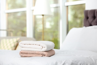 Photo of Stack of clean terry towels on bed. Space for text