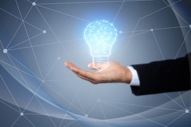 Idea concept. Businessman demonstrating glowing light bulb illustration on grey background, closeup
