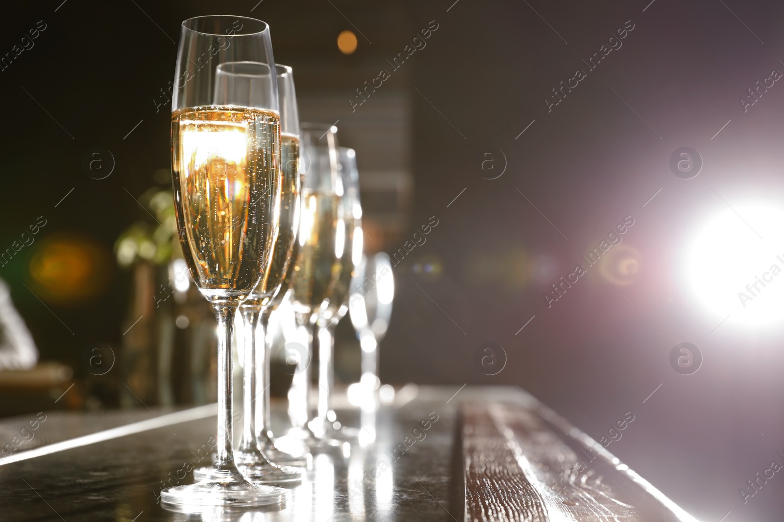 Photo of Glasses of champagne on counter in bar. Space for text