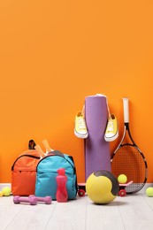 Many different sports equipment near orange wall indoors