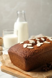 Photo of Delicious gingerbread cake with almond petals on table, space for text