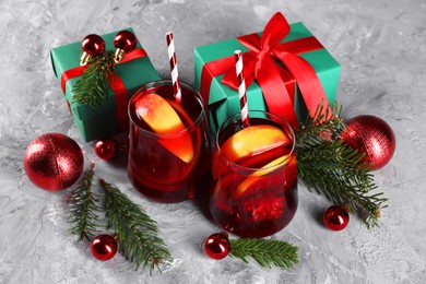 Photo of Delicious Sangria drink in glasses and Christmas decorations on grey textured table