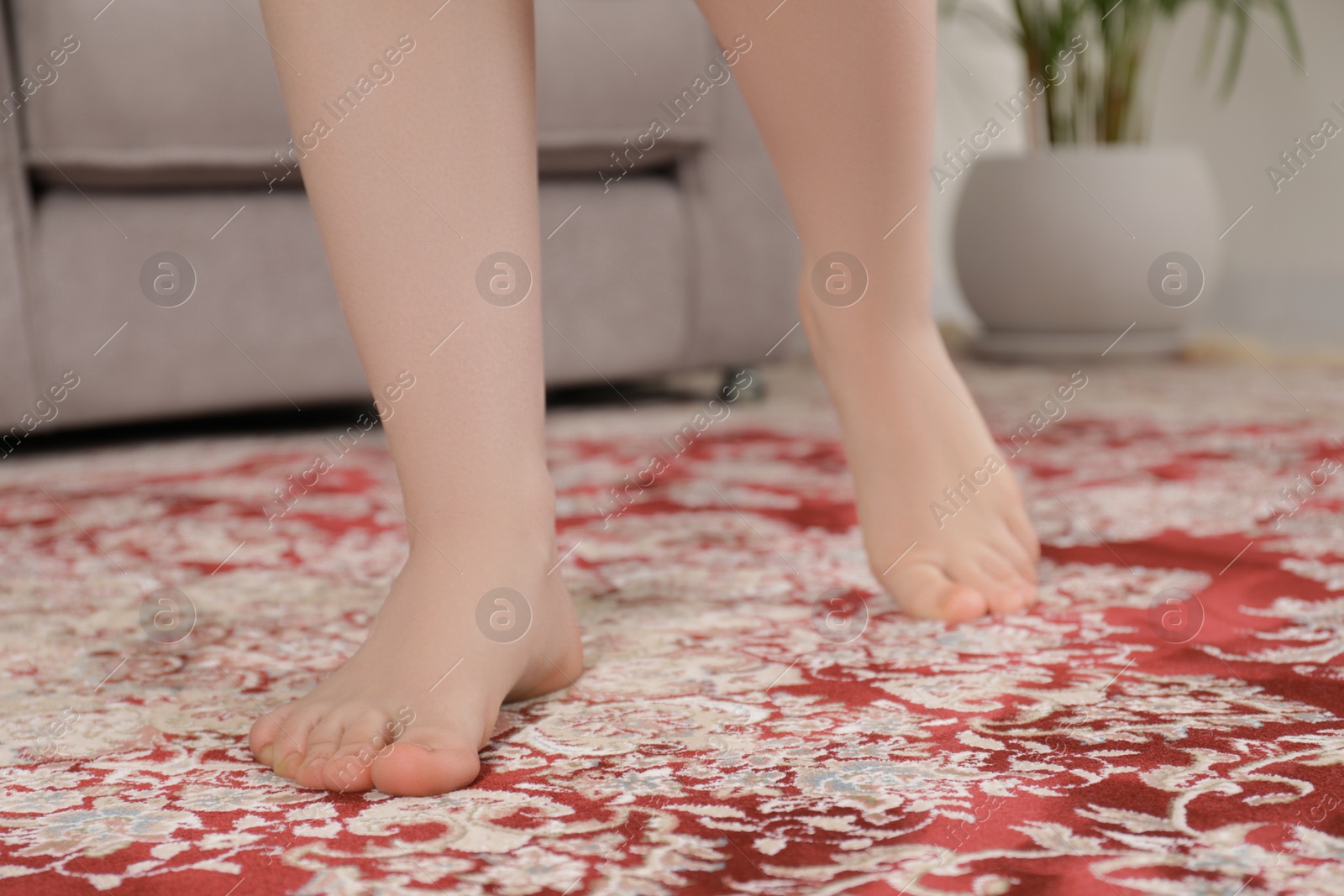 Photo of Woman standing on carpet with pattern at home, closeup