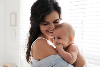 Photo of Happy young mother with her cute baby near window at home