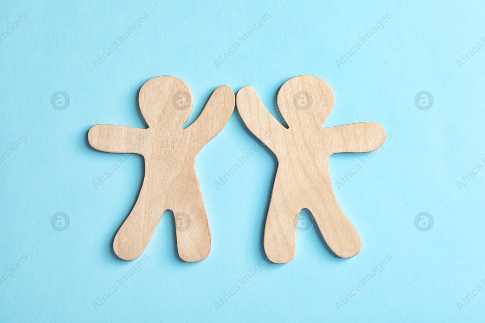 Photo of Wooden people giving high five on color background. Unity concept