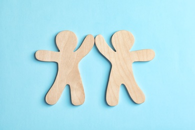 Photo of Wooden people giving high five on color background. Unity concept