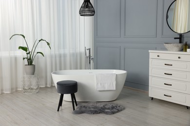 Stylish bathroom interior with beautiful tub, stool and houseplant