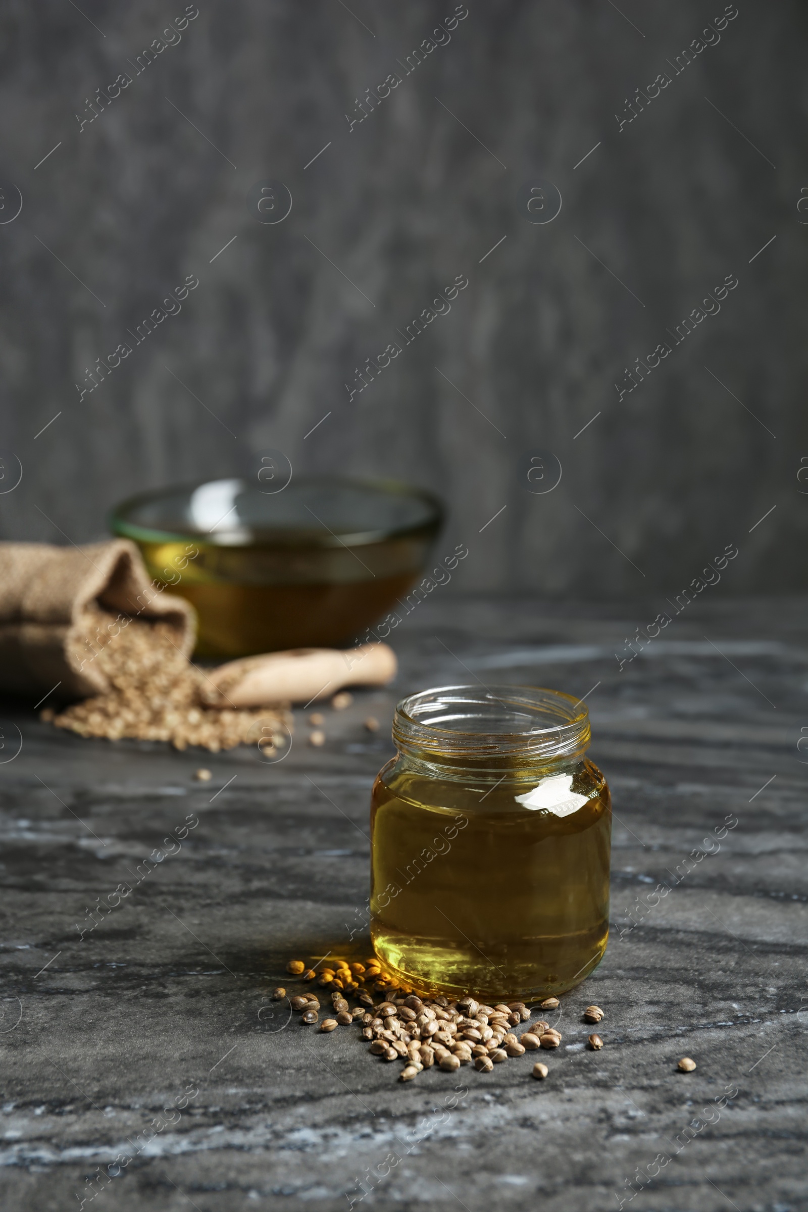 Photo of Jar with hemp oil on grey table