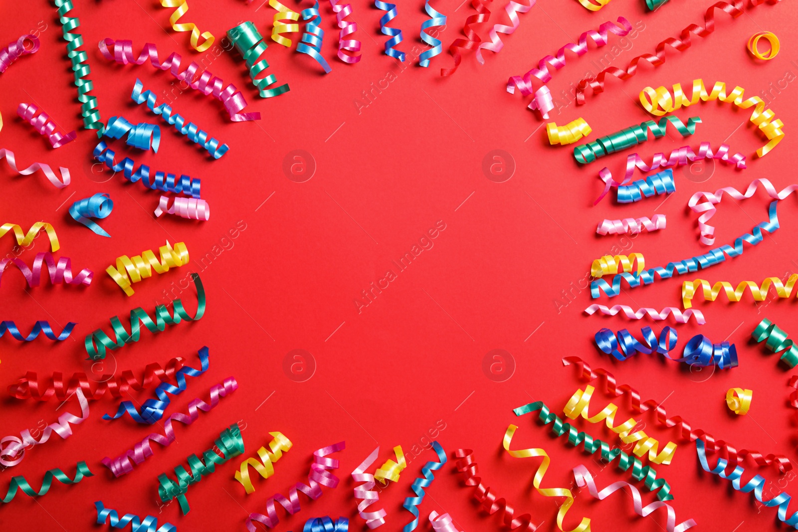 Photo of Frame of colorful serpentine streamers on red background, flat lay. Space for text