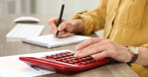 Photo of Professional accountant using calculator at wooden desk in office, closeup