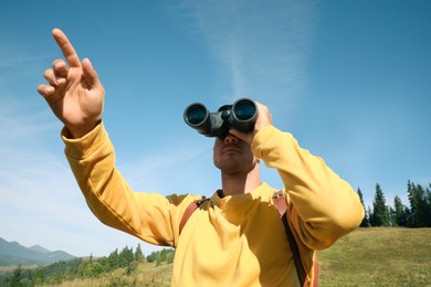 Man with binoculars in mountains on sunny day