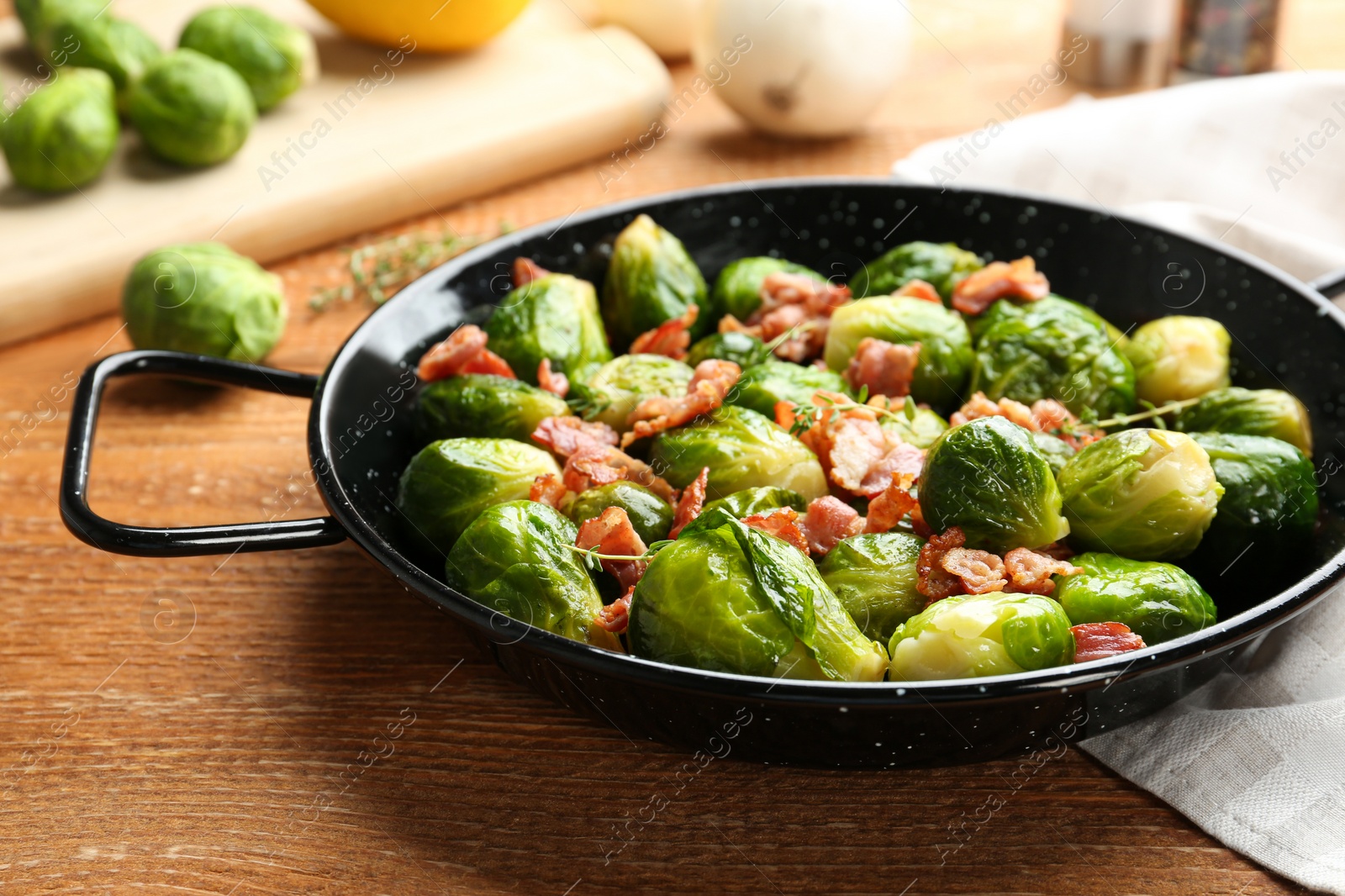 Photo of Tasty roasted Brussels sprouts with bacon on wooden table, closeup