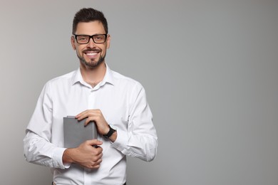 Photo of Happy teacher with glasses and book against beige background. Space for text