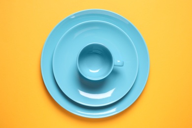 Photo of New ceramic dishware on yellow background, top view