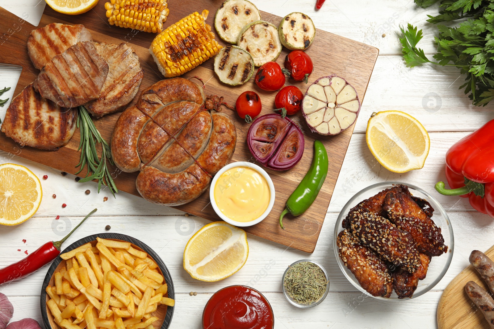 Photo of Flat lay composition with barbecued meat and vegetables on white wooden table