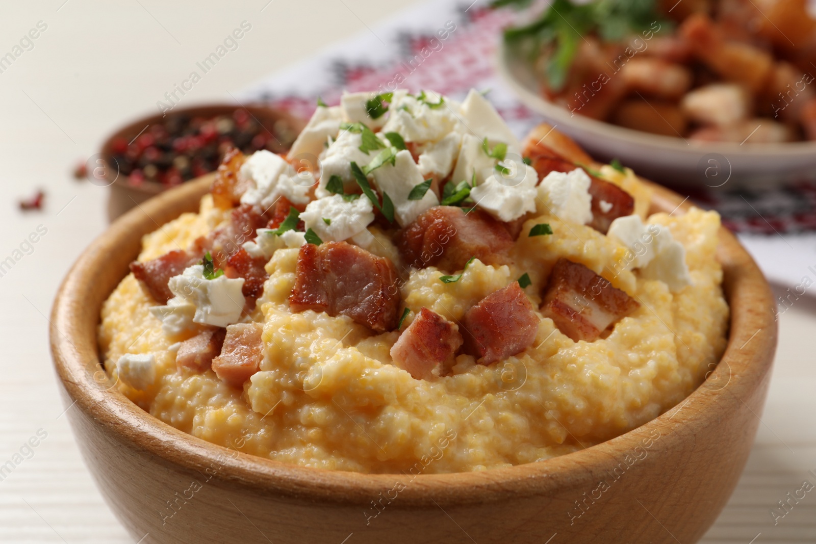 Photo of Delicious traditional Ukrainian banosh in wooden bowl on light table, closeup