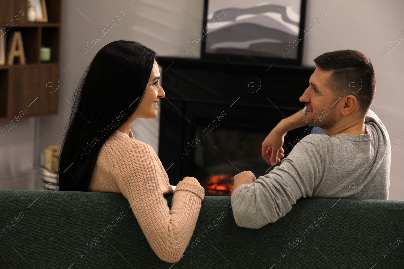 Photo of Lovely couple spending time together on sofa near fireplace at home