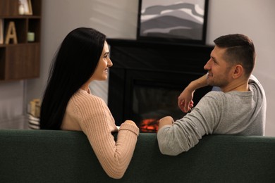 Lovely couple spending time together on sofa near fireplace at home